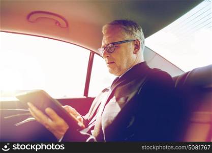 transport, business trip, technology and people concept - senior businessman with tablet pc computer driving on car back seat. senior businessman with tablet pc driving in car
