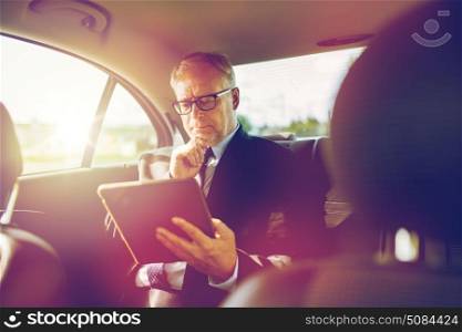 transport, business trip, technology and people concept - senior businessman with tablet pc computer driving on car back seat. senior businessman with tablet pc driving in car. senior businessman with tablet pc driving in car