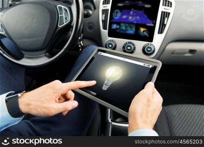 transport, business trip, technology, innovation and people concept - close up of male hands holding tablet pc computer with light bulb icon on screen in car