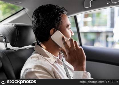 transport, communication and business concept - indian male passenger or businessman calling on smartphone on back seat of taxi car. male passenger calling on smartphone in taxi car