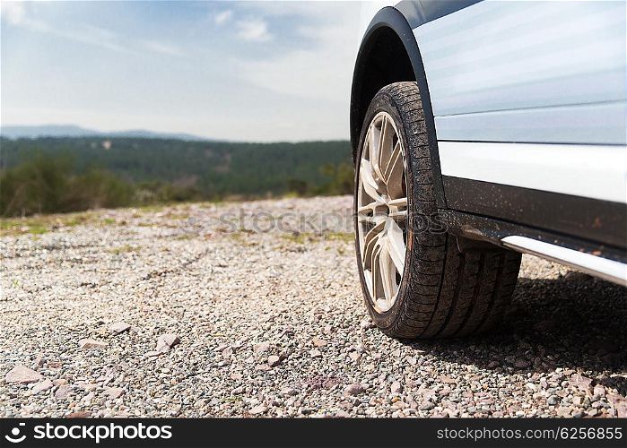 transport, driving and motor vehicle concept - close up of dirty car wheel on cliff