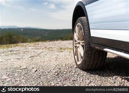 transport, driving and motor vehicle concept - close up of dirty car wheel on cliff