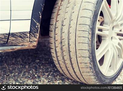 transport, driving and motor vehicle concept - close up of dirty car wheel on ground