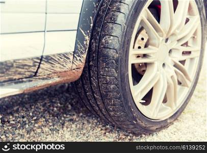 transport, driving and motor vehicle concept - close up of dirty car wheel on ground
