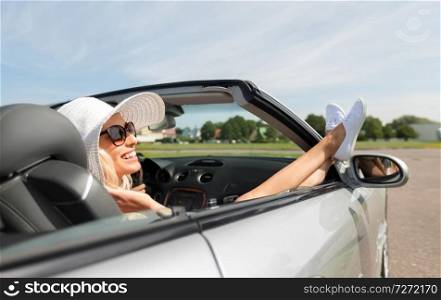 transport, leisure and people concept - happy woman in summer hat and sunglasses chilling in cabriolet car outdoors. happy woman driving in cabriolet car