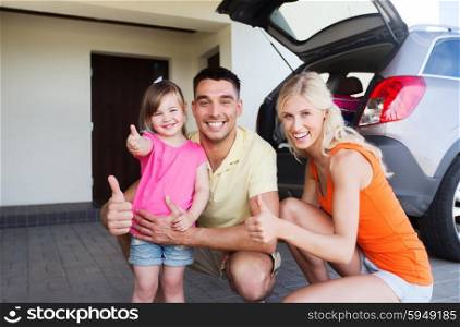 transport, leisure, road trip and people concept - happy family with little girl and hatchback car showing thumbs up at home parking space