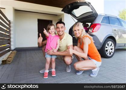 transport, leisure, road trip and people concept - happy family with little girl and hatchback car showing thumbs up at home parking space