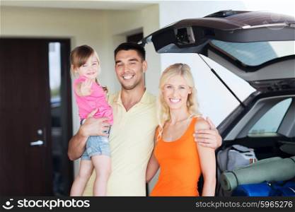 transport, leisure, road trip, travel and people concept - happy family with little girl packing things hatchback car at home parking space