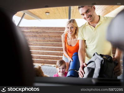 transport, leisure, travel, road trip and people concept - happy family packing things into car at home parking