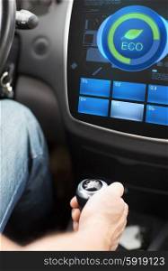 transport, modern, green energy, technology and people concept - male hand on gearshift and car eco system mode on screen