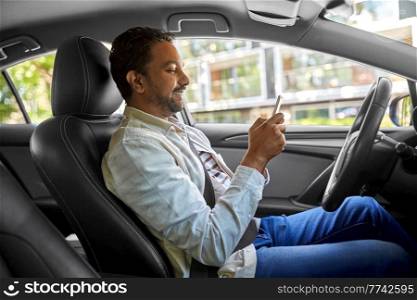 transport, people and technology concept - smiling indian man or driver using smartphone in car. smiling indian man in car using smartphone