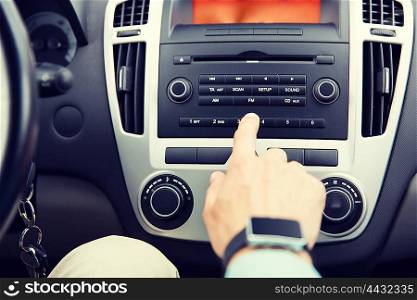 transport, road trip, car driving, technology and people concept - close up of male hand turning on radio on control panel system in car