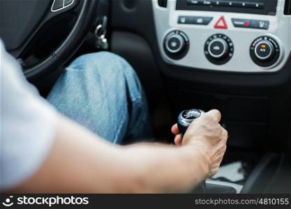 transport, road trip, speed and people concept - close up of young man driving car and using gear shift