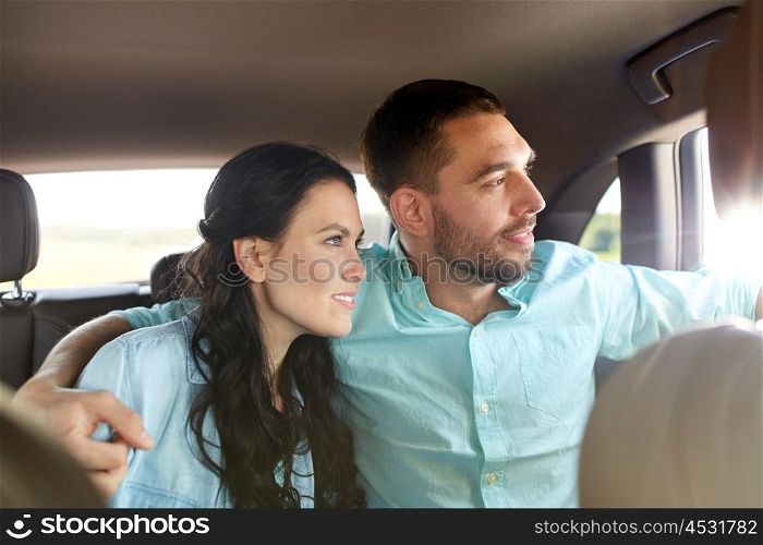 transport, road trip, travel, family and people concept - happy man and woman hugging in car and looking to window
