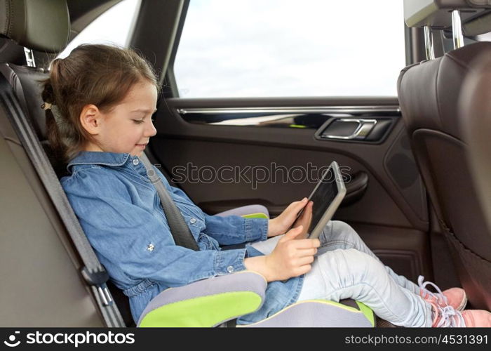 transport, road trip, travel, technology and people concept - happy little girl with tablet pc driving in car safety seat