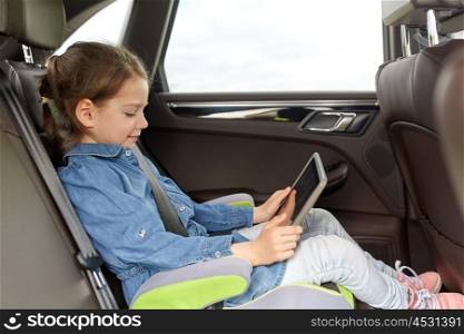 transport, road trip, travel, technology and people concept - happy little girl with tablet pc driving in car safety seat
