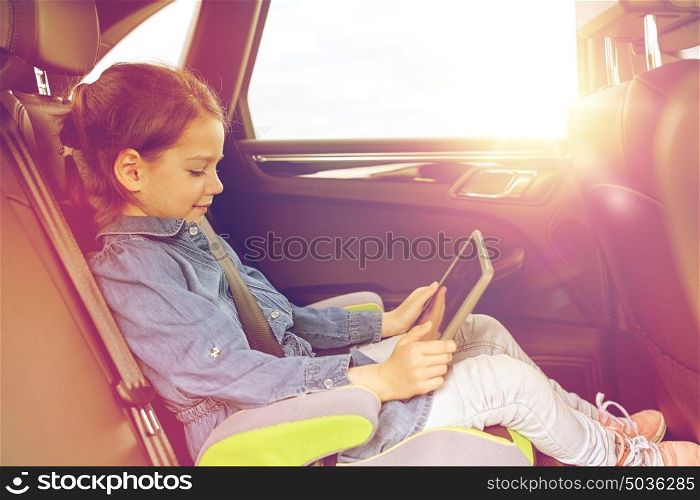 transport, road trip, travel, technology and people concept - happy little girl with tablet pc driving in car safety seat. happy little girl with tablet pc driving in car