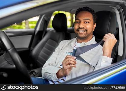 transport, safety and people concept - happy smiling indian man or driver fastening seat belt in car. smiling indian driver fastening seat belt in car