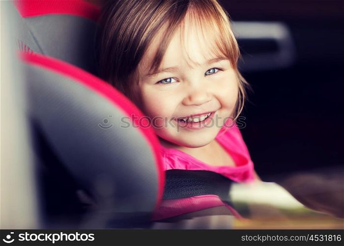 transport, safety, childhood road trip and people concept - happy little girl sitting in baby car seat