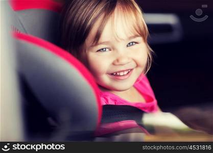 transport, safety, childhood road trip and people concept - happy little girl sitting in baby car seat