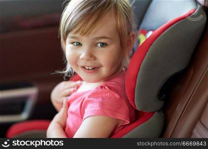 transport, safety, road trip and childhood concept - close up of happy little girl sitting in baby car seat. close up of little girl sitting in baby car seat. close up of little girl sitting in baby car seat