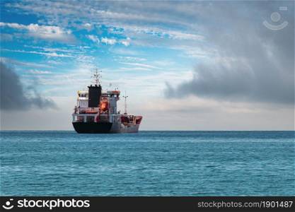 Transport ship traveling in open sea in cloudy weather.