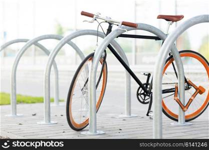 transport, storage, security and safety concept - close up of fixed gear bicycle locked at street parking outdoors