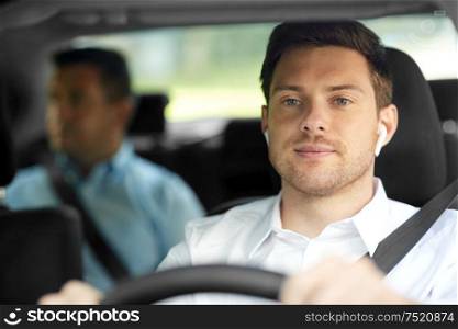 transport, taxi and people concept - male driver with wireless earphones or hands free device driving car with passenger. male driver with wireless earphones driving car