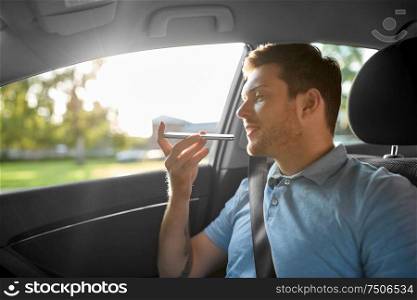 transport, technology and communication concept - male passenger using voice command recorder on smartphone on back seat of taxi car. passenger recording voice on smartphone in car