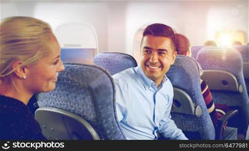 transport, tourism and air flights concept - happy passengers or tourists talking in plane over porthole background. happy passengers talking in plane. happy passengers talking in plane