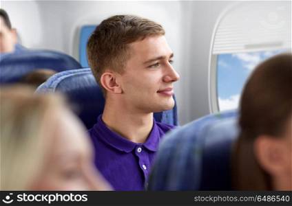 transport, tourism and air flights concept - happy young man travelling by plane over porthole background. happy young man travelling by plane. happy young man travelling by plane
