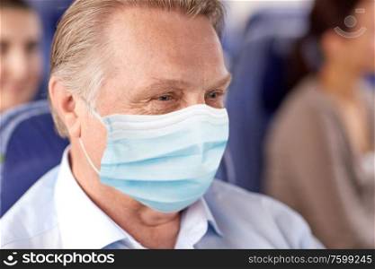 transport, tourism and pandemic concept - close up of senior male passenger wearing protective medical mask for protection from virus sitting in travel bus or airplane. senior passenger in mask in travel bus or airplane