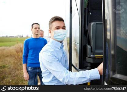 transport, tourism and pandemic concept - male passenger wearing protective medical mask for protection from virus boarding travel bus. male passenger in medical mask boarding travel bus
