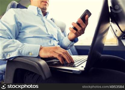 transport, tourism, business trip and people concept - close up of man with smartphone and laptop in travel bus. man with smartphone and laptop in travel bus