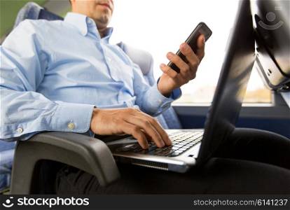 transport, tourism, business trip and people concept - close up of man with smartphone and laptop in travel bus