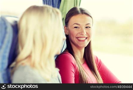 transport, tourism, friendship, road trip and people concept - happy young women sitting and talking in travel bus. happy young women sitting in travel bus