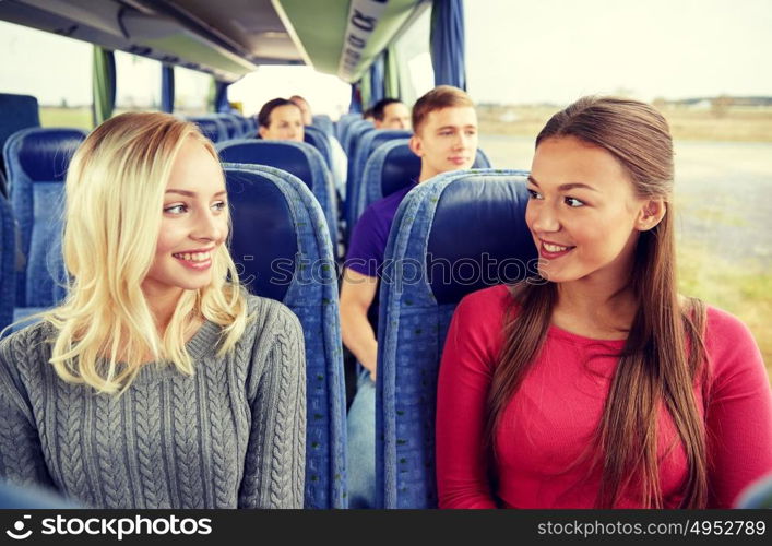 transport, tourism, friendship, road trip and people concept - happy young women sitting and talking in travel bus. happy young women talking in travel bus