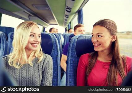 transport, tourism, friendship, road trip and people concept - happy young women sitting and talking in travel bus. happy young women talking in travel bus
