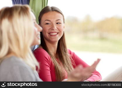 transport, tourism, friendship, road trip and people concept - happy young women sitting and talking in travel bus or train