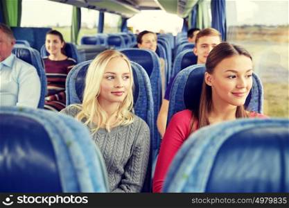 transport, tourism, friendship, road trip and people concept - young women or teenage friends riding in travel bus. happy young women riding in travel bus