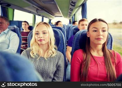 transport, tourism, friendship, road trip and people concept - young women or teenage friends riding in travel bus. happy young women riding in travel bus