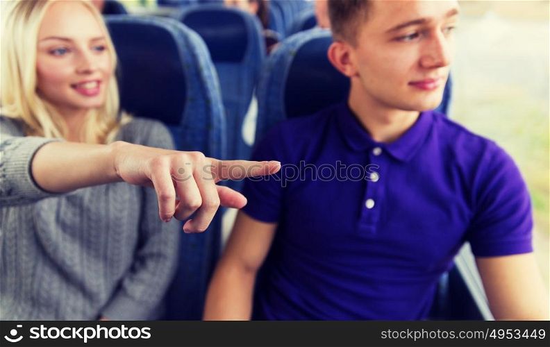 transport, tourism, road trip and people concept - close up of young couple driving in travel bus and pointing finger to something outside. close up of young couple driving in travel bus