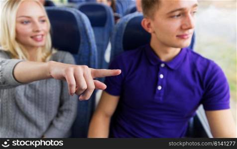 transport, tourism, road trip and people concept - close up of young couple driving in travel bus and pointing finger to something outside