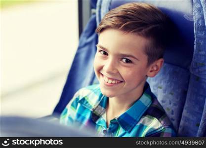 transport, tourism, road trip and people concept - happy boy sitting in travel bus or train. happy boy sitting in travel bus or train