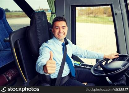 transport, tourism, road trip and people concept - happy driver driving intercity bus and snowing thumbs up. happy driver driving bus and snowing thumbs up