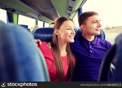transport, tourism, road trip and people concept - happy teenage couple or tourists hugging in travel bus and looking through window. happy teenage couple or passengers in travel bus