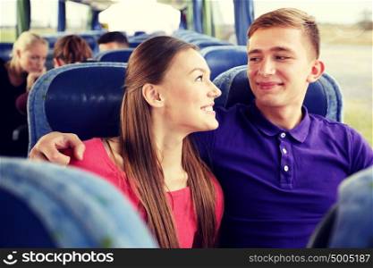 transport, tourism, road trip and people concept - happy teenage couple or tourists in travel bus hugging and talking. happy teenage couple or passengers in travel bus