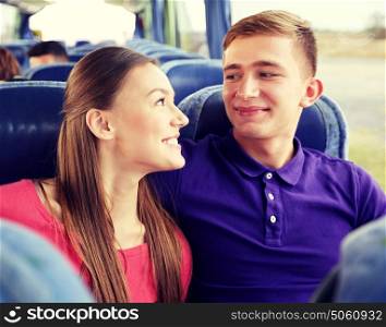 transport, tourism, road trip and people concept - happy teenage couple or tourists in travel bus hugging and talking. happy teenage couple or passengers in travel bus