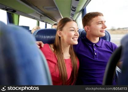 transport, tourism, road trip and people concept - happy teenage couple or tourists hugging in travel bus and looking through window
