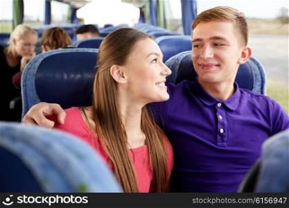 transport, tourism, road trip and people concept - happy teenage couple or tourists in travel bus hugging and talking